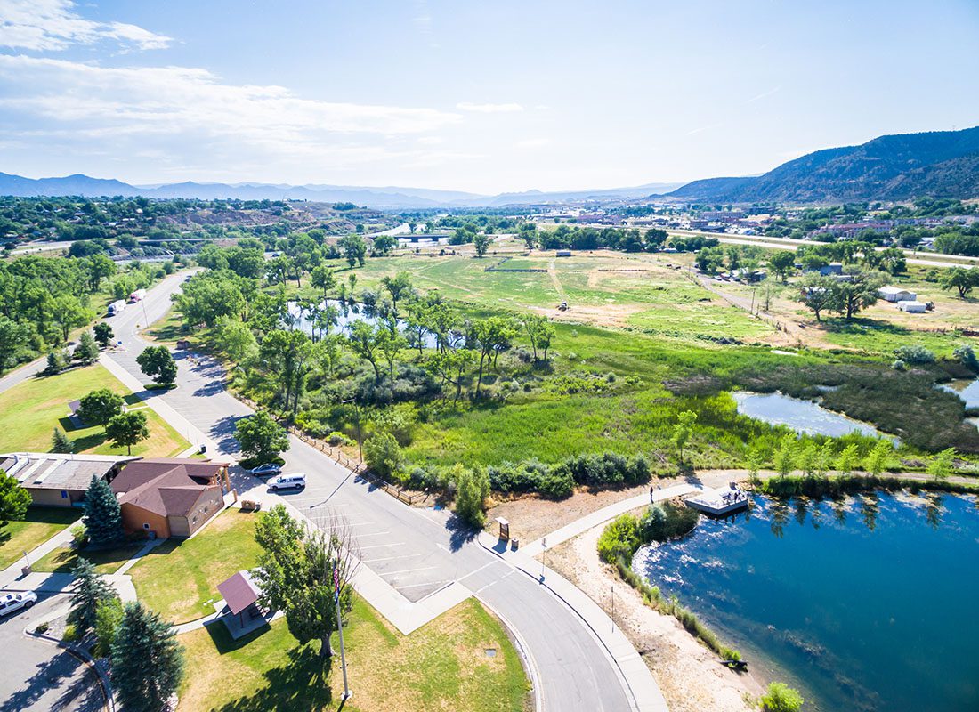 Rifle, CO - Commercial Building Surrounded by Green Trees and Grass with Mountains in the Background Next to the Colorado River in Rifle Colorado